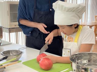 包丁でトマトの薄皮だけ切れ目を入れるお子さん 包丁でトマトの薄皮だけ切れ目を入れるお子さん
