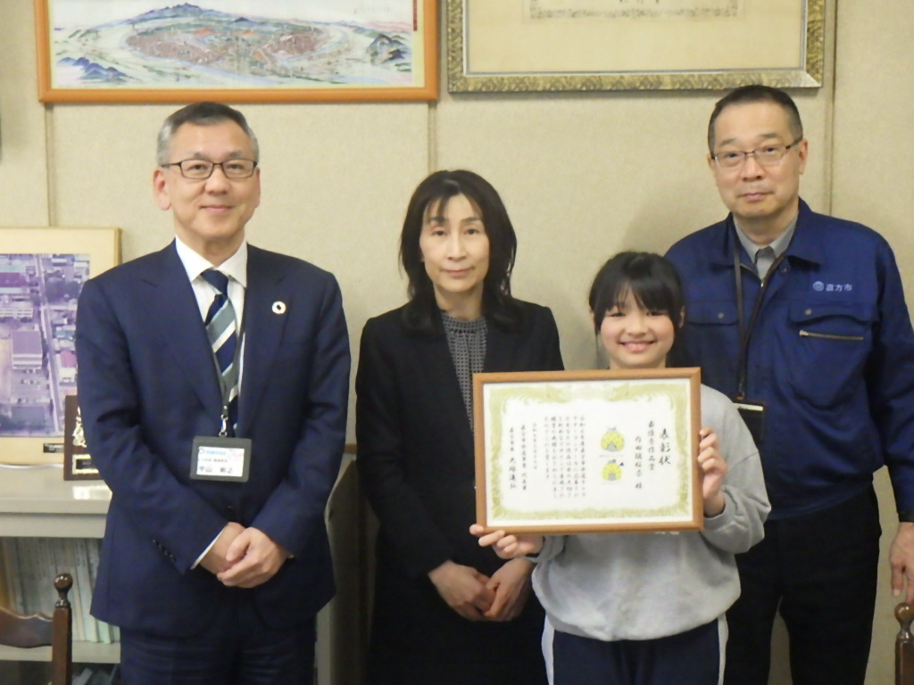 記念撮影(左より上下水道・環境部長 宇山裕之、下元 操校長、内田璃桜奈さん、水道施設課長 山本正光)