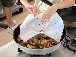 作った落し蓋をフライパンにセットするお子さん