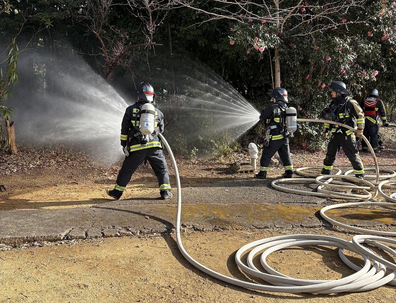 消防隊員2名が山林に向かって放水している。