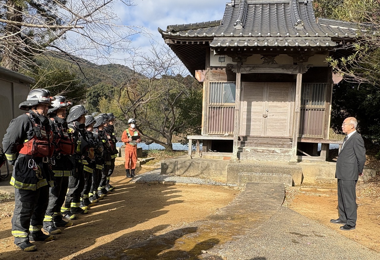 法華寺観音堂の前で山本教育長が隊員に話しかけている。